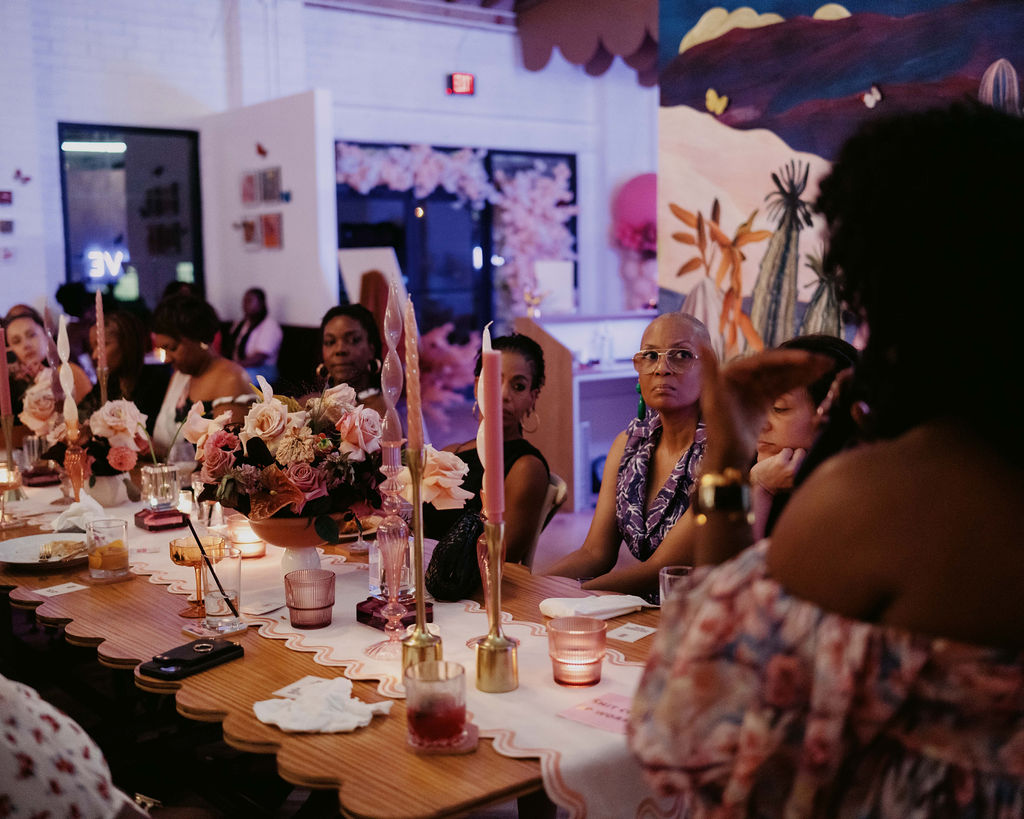 Guests engaged in conversation and listening during the design talk at the Aroma & Ambiance event by Indigo Pruitt Designs, seated at elegantly decorated tables with floral centerpieces