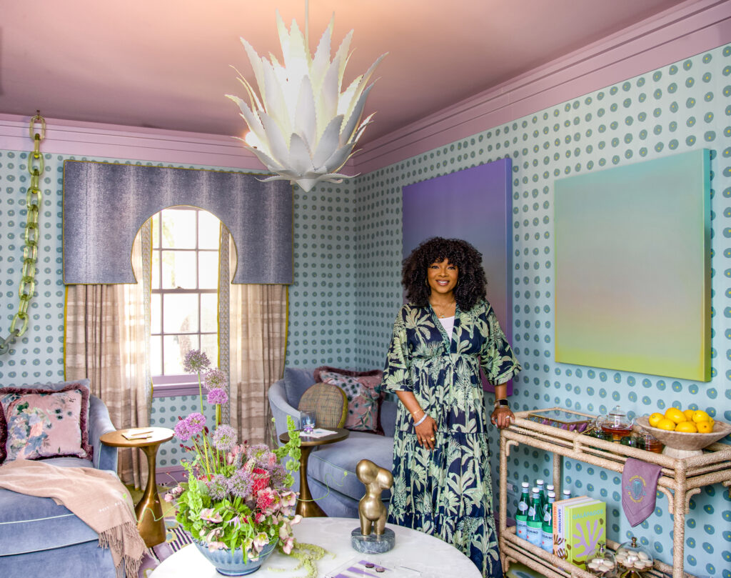 Interior designer Marie Cloud in her Kips Bay Showhouse space, featuring custom wallpaper, layered textiles, bold abstract art, and a statement chandelier. The room blends vibrant colors, organic forms, and curated styling, reflecting her signature approach to storytelling through design.